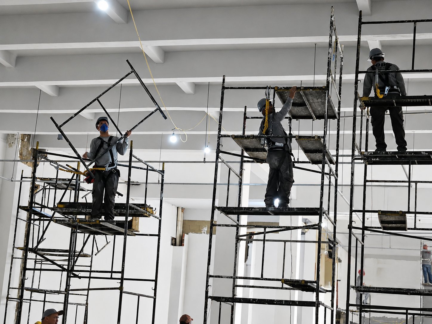Equipe realizando instalação elétrica em altura com andaimes